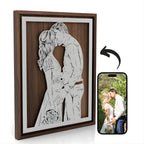 Framed anniversary portrait of a couple kissing on their wedding day, steel in a walnut frame, next to the wedding photo it was drawn from